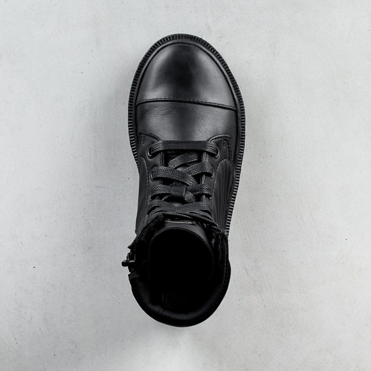 A single black leather lace-up ankle boot shown from a top-down view on a light gray textured background.