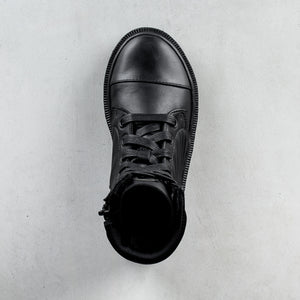 A single black leather lace-up ankle boot shown from a top-down view on a light gray textured background.