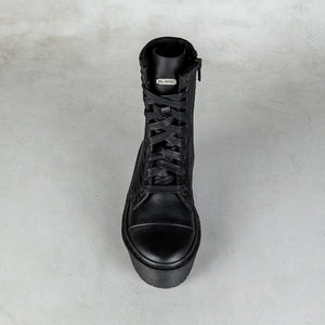 A single black leather lace-up ankle boot with a side zipper, shown from a top-down perspective on a textured light gray background.