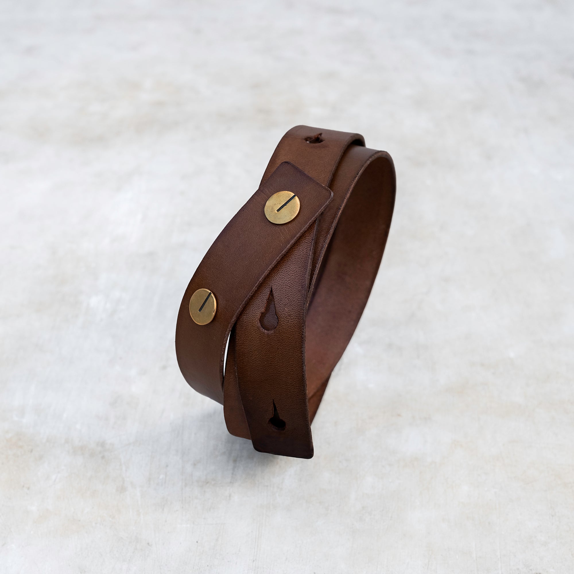 Leather strap belt in brown with brass buttons
