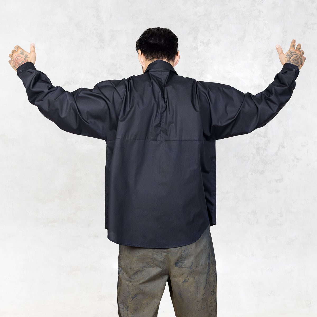 Person wearing a black shirt with arms outstretched against a light gray background