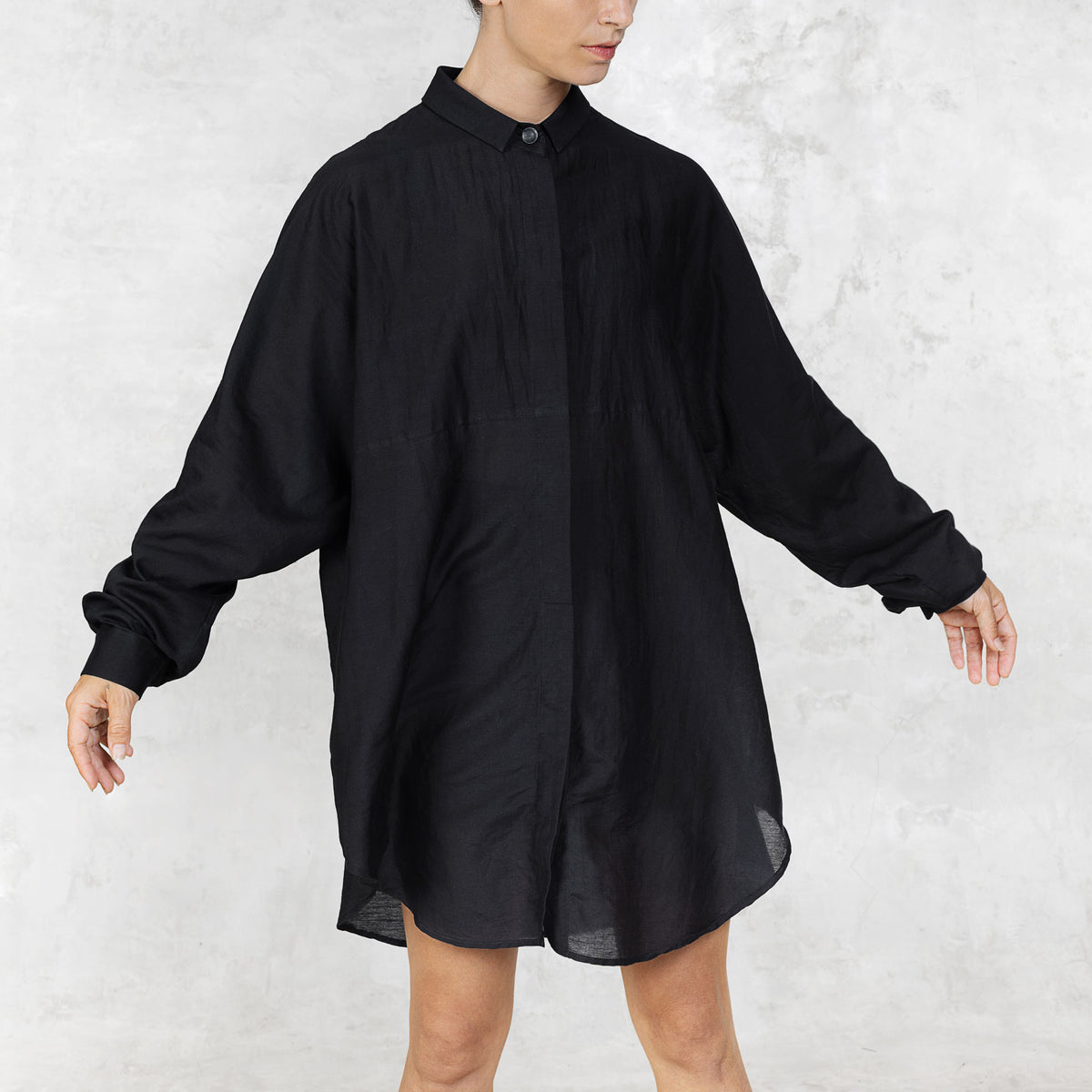 Person wearing a black shirt dress against a white background