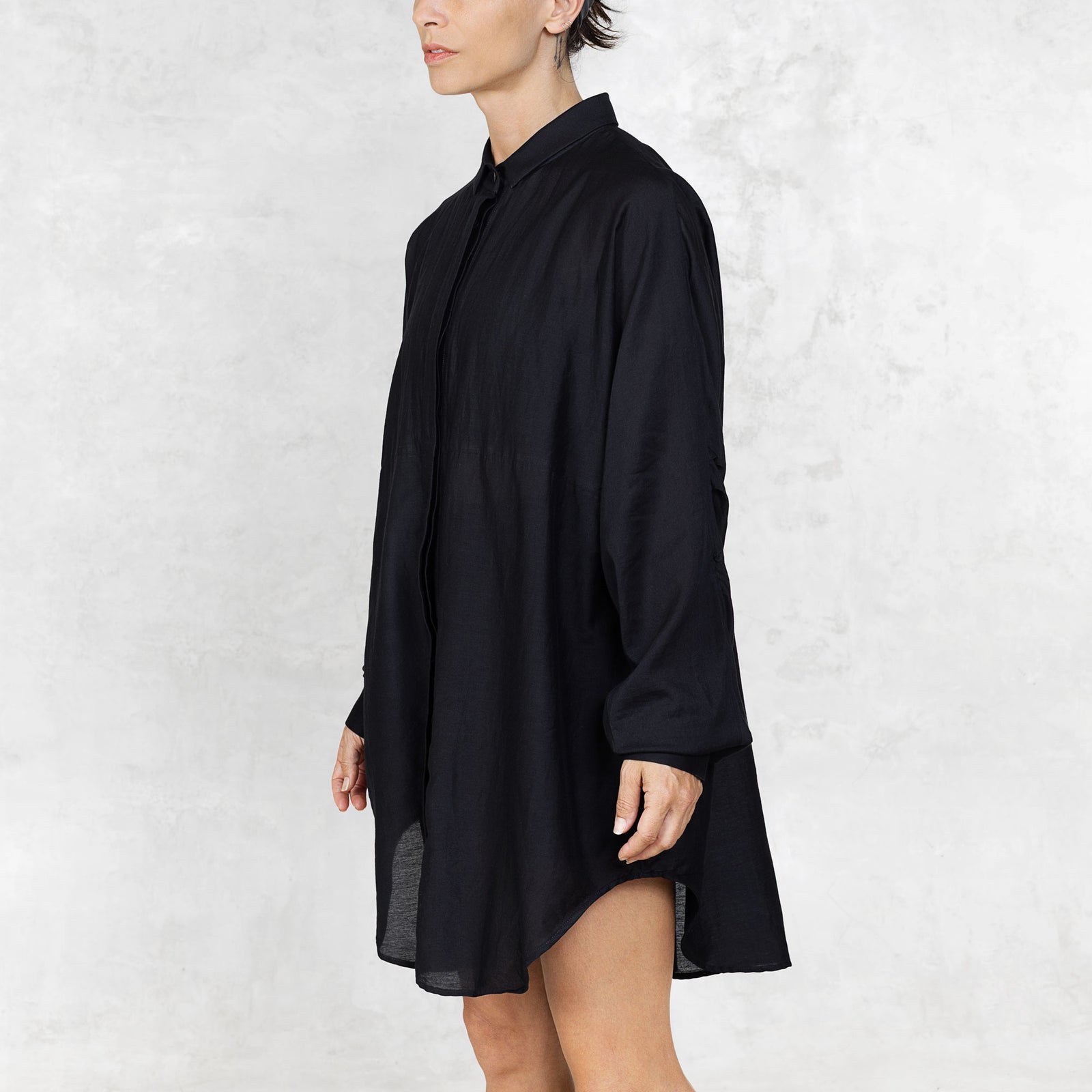 Person wearing a black oversized shirt against a white background