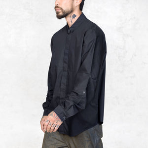 Person with tattoos wearing a black shirt against a white background