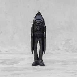 A black wooden raven person statuette  against a light gray background
