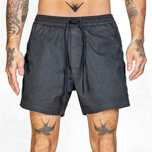Person wearing black shorts with tattoos on arms and legs against a white background