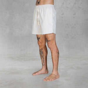 3/4 view of a person from feet to waist wearing mid-thigh shorts in hand painted bone against a gray background