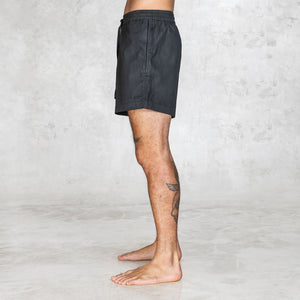 Side view of black mid-thigh shorts with lightweight zippered pocket and clean no-back-pocket design.