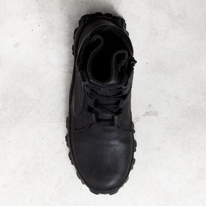 Top down view of a black textured leather boot against a light gray background. 