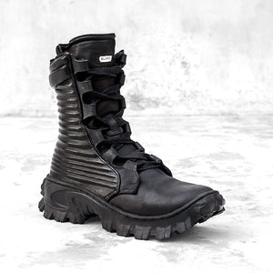 Quarter view of a black textured leather boot against a light gray background. 