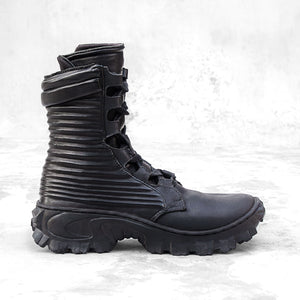 Side profile of a black textured leather boot against a light gray background. 