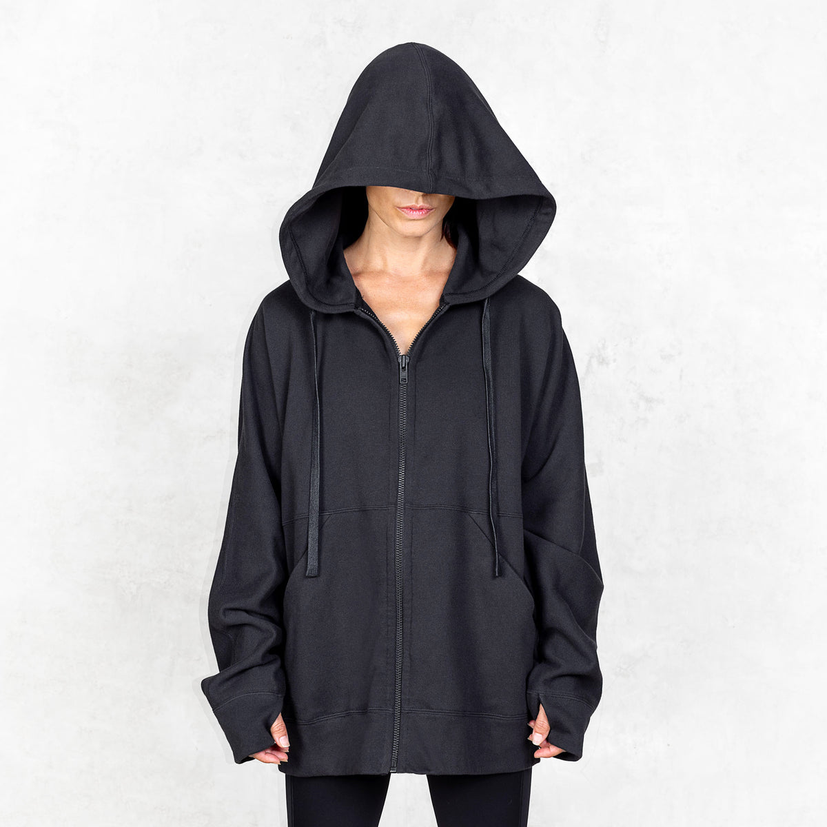 Person wearing a black hoodie with a plain background