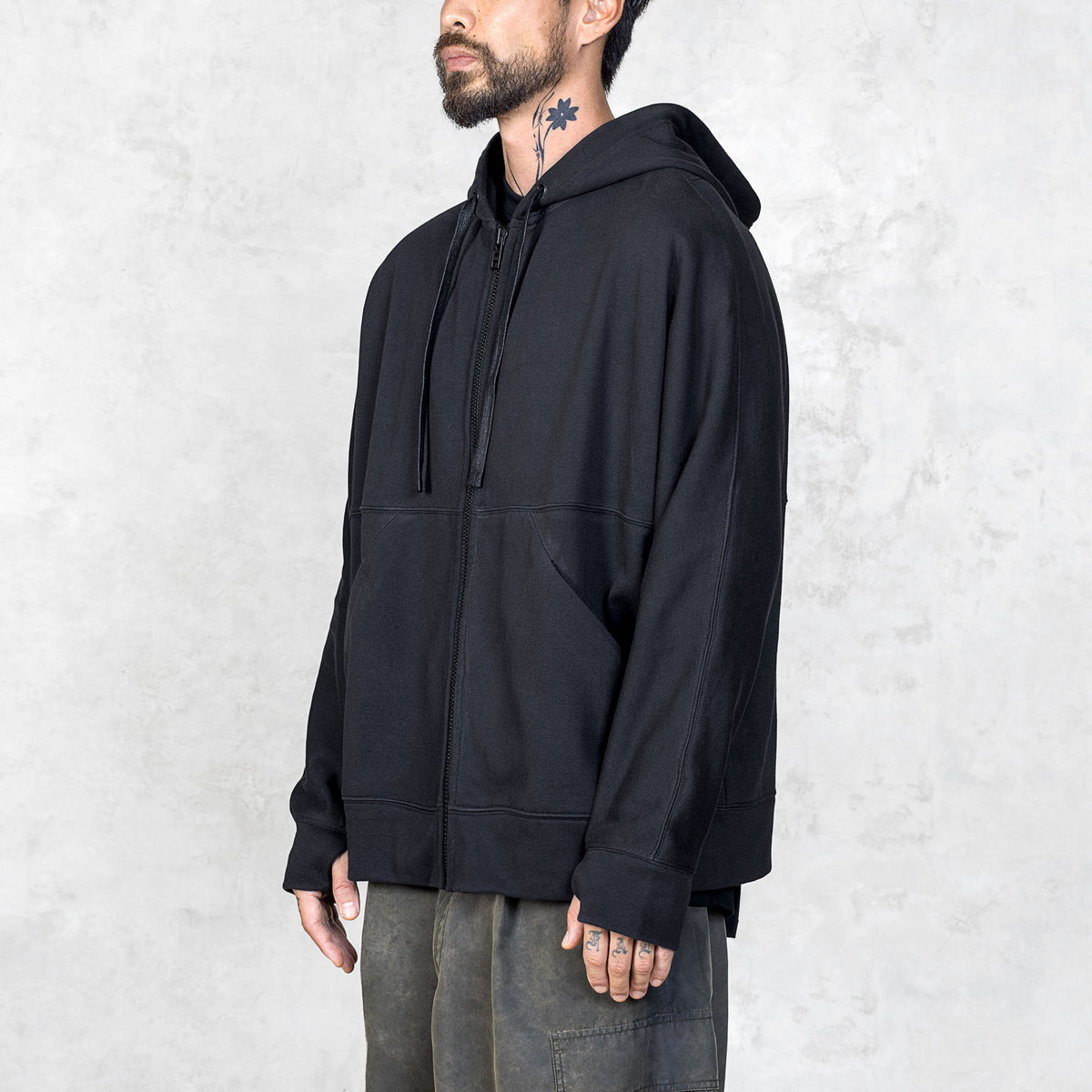 Quarter view of a Person wearing a black zip-up hoodie against a plain background