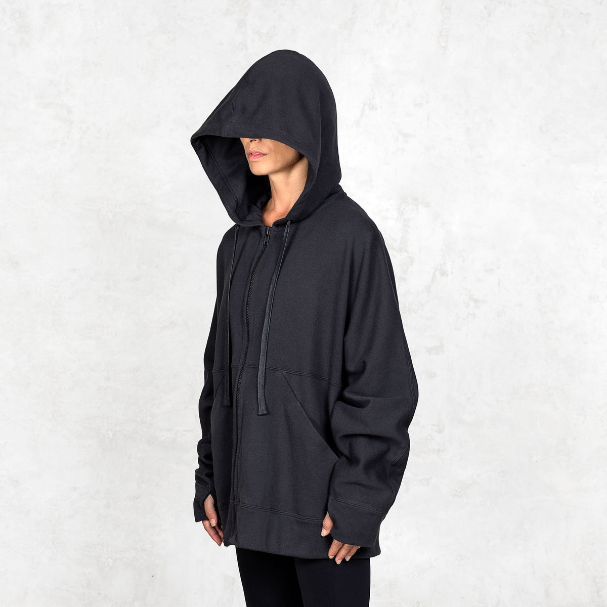 3/4 view of a person wearing a black hoodie against a white background