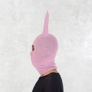 Person facing sideways wearing a pink mask with long spikey ears on a white background