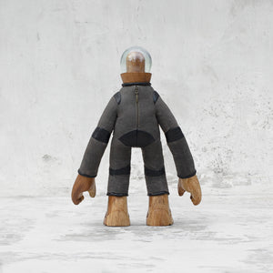 Back view of a leather wood and glass astronaut statuette with a zipper standing against a light gray background