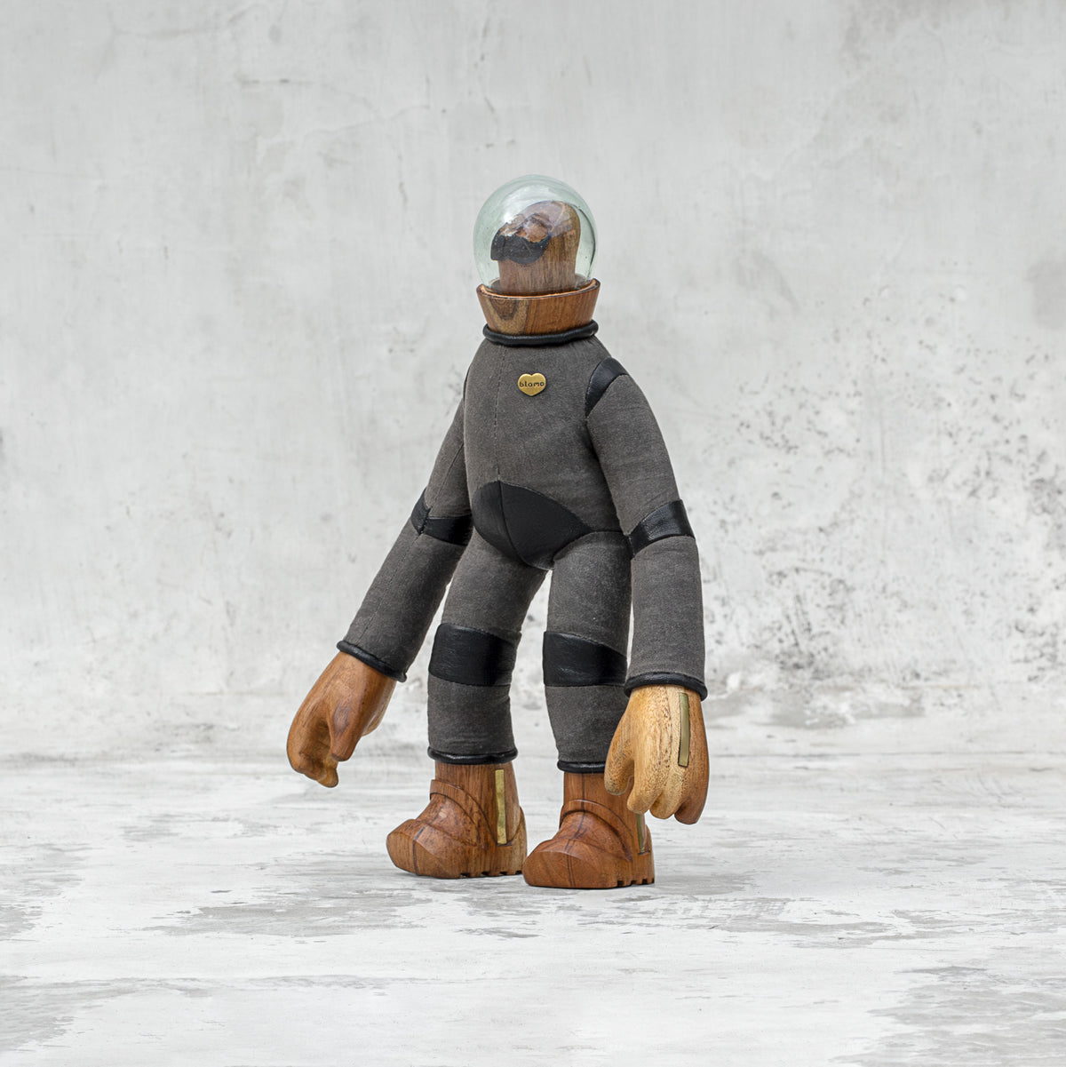 Leather wood and glass astronaut with a mustache statuette facing sideways standing against a light gray background
