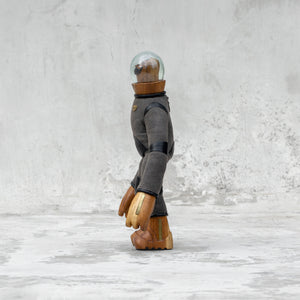 Side view of a leather wood and glass astronaut with a mustache statuette standing against a light gray background