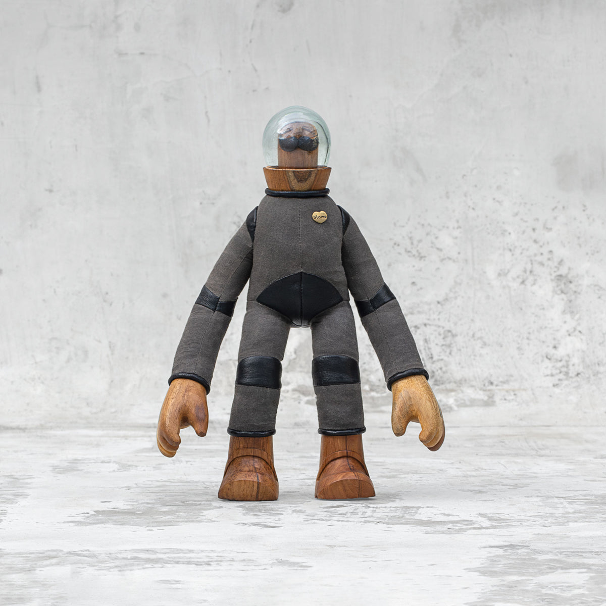 Leather wood and glass astronaut with a mustache statuette standing against a light gray background