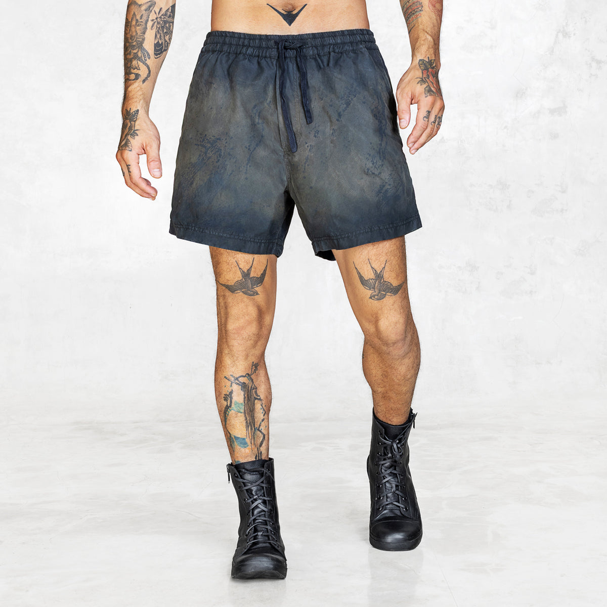 Person wearing dark shorts and black boots on a white background