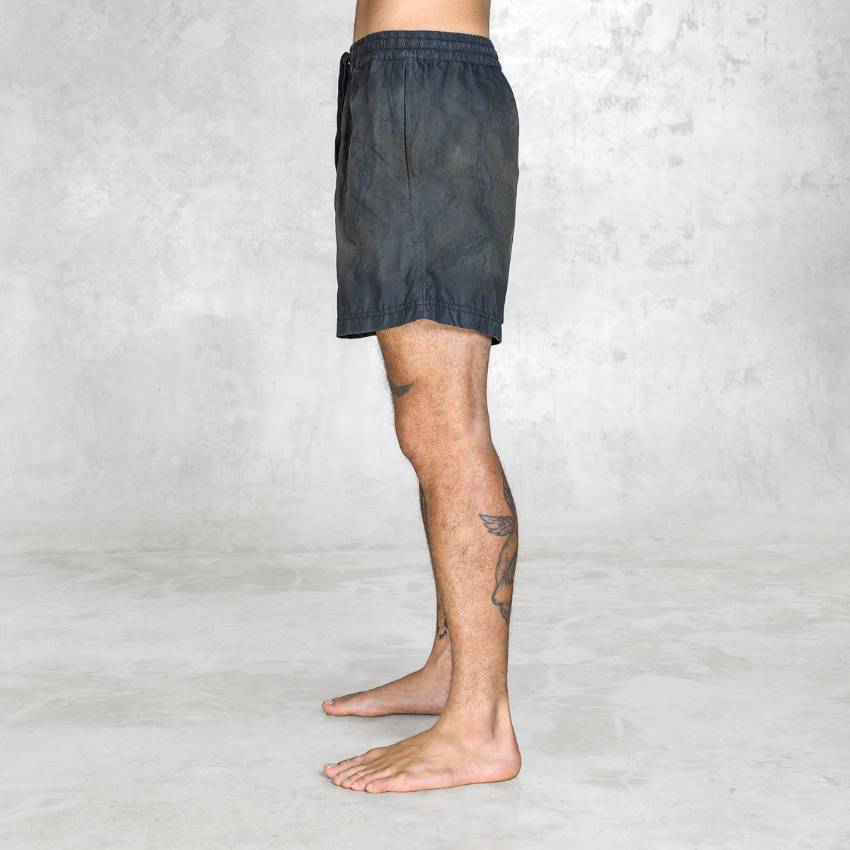 Side view of a Person wearing olive painted shorts on a plain background