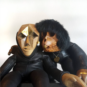 Two wooden and leather figurines against a white background