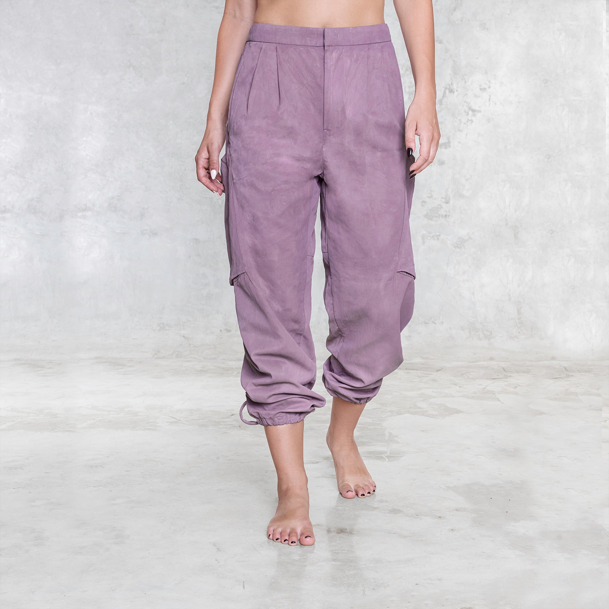 A woman standing facing front wearing a pair of dark pink rose silk cargo style BLAMO pants