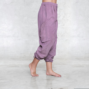 A woman standing facing sideways pictured from the feet to the waist wearing a pair of dark pink rose silk cargo style BLAMO pants