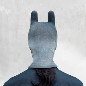 An man from the shoulders up facing back wearing an indigo ombre balaclava