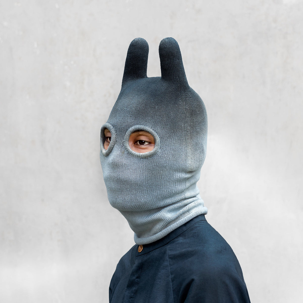 An man from the shoulders up wearing an indigo ombre balaclava