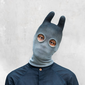 An man from the shoulders up wearing an indigo ombre balaclava