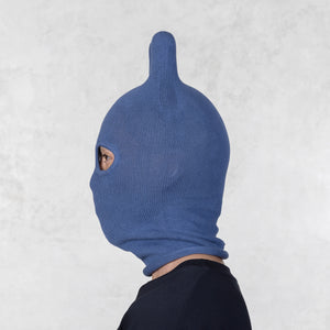 Person wearing a blue knitted balaclava with rounded ears on a light gray background
