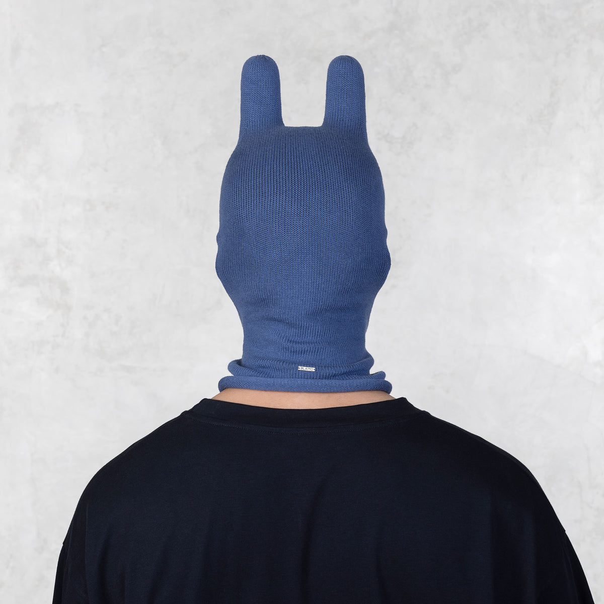 Person wearing a blue balaclava against a light gray background