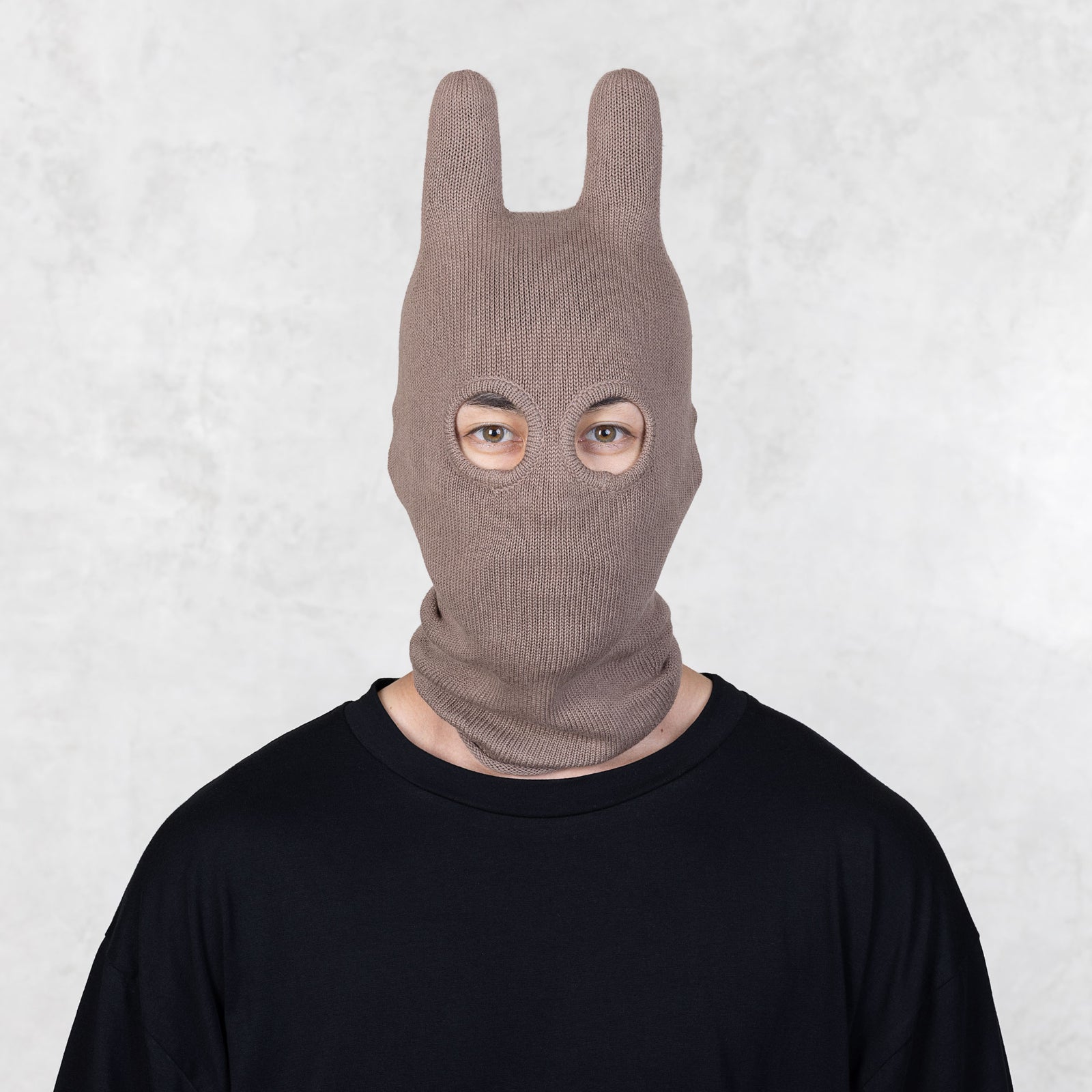 Person wearing a brown bunny mask against a white background