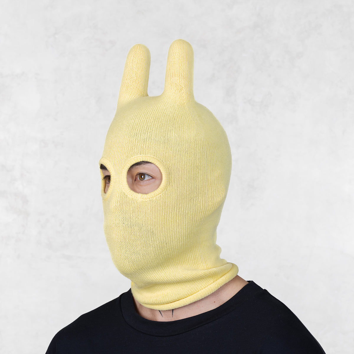 Person wearing a Blamo Socky Lemon Balaclava yellow bunny mask against a light gray background