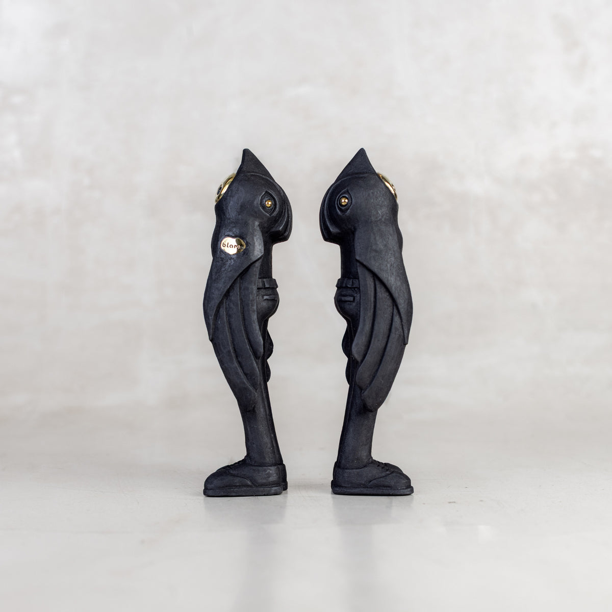 Side view of two black birdman figurines on a white background