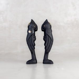 Side view of two black birdman figurines on a white background