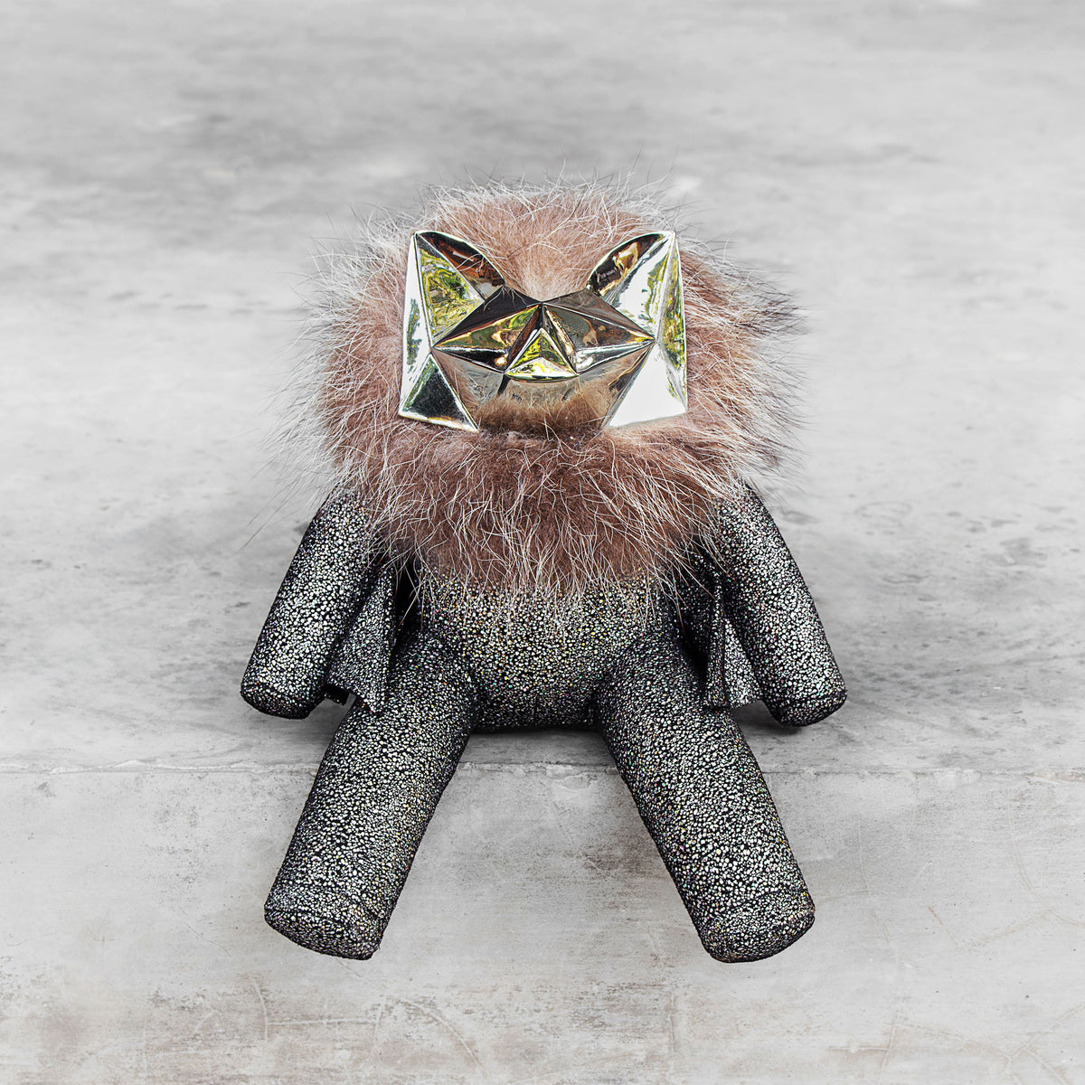 Sparkly leather stuffed toy with a brass head and fur on a gray background
