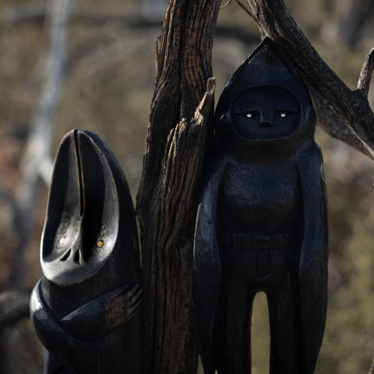 Dark wooden sculptures against a natural background