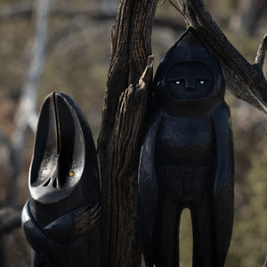 Dark wooden sculptures against a natural background