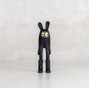 Black bunny figure with gold eyes on a white background