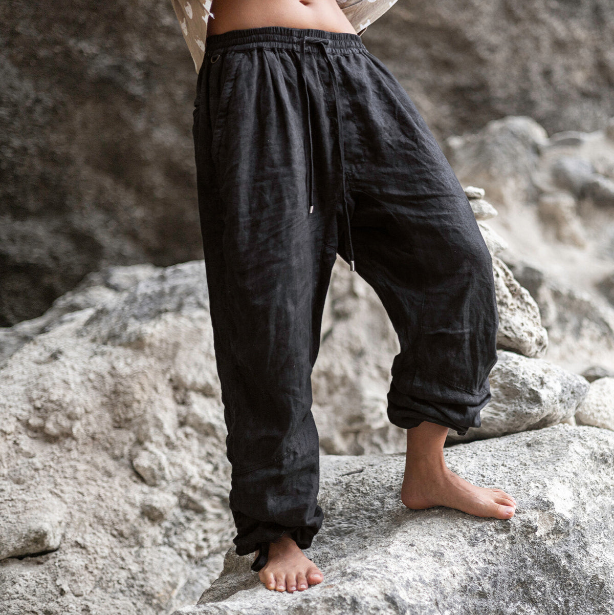 Person wearing dark linen pants standing on rocks with a natural background