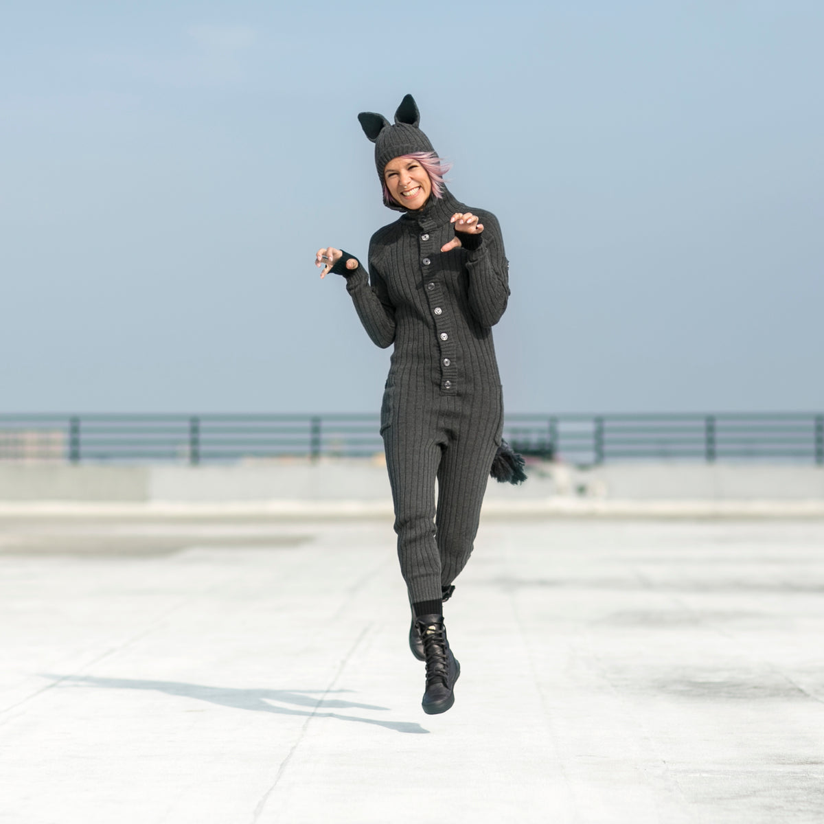 Person wearing a wolf onesie on a concrete surface with clear blue skies