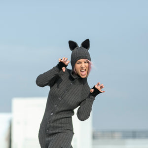 person wearing a wolf onesie with their mouth open and hands shaped like claws with a clear sky in the background