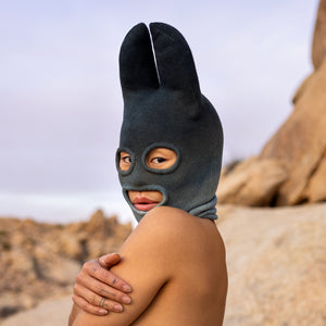 A woman from the shoulders up wearing a cotton Knit Bat balaclava in faded indigo
