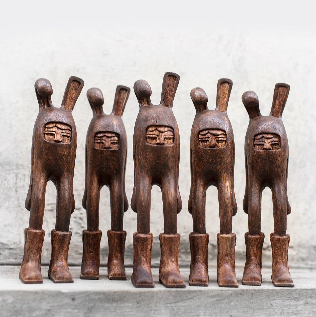 Set of six wooden bunny rabbit figurines with carved faces on a neutral background
