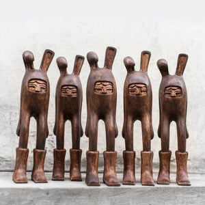 Set of six wooden figurines with carved faces on a neutral background