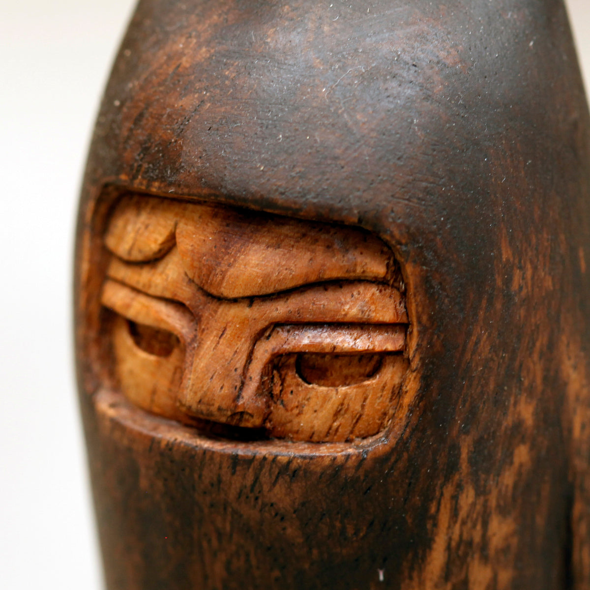 Close-up of a wooden face with intricate carvings on a white background