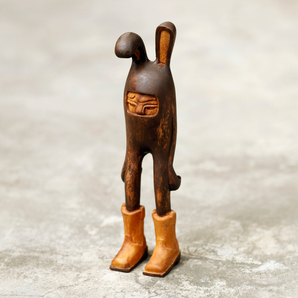 Wooden rabbit figurine with a face on a textured surface