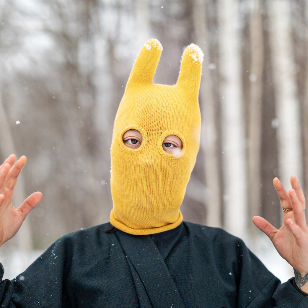 Person wearing a yellow bunny mask in a snowy forest